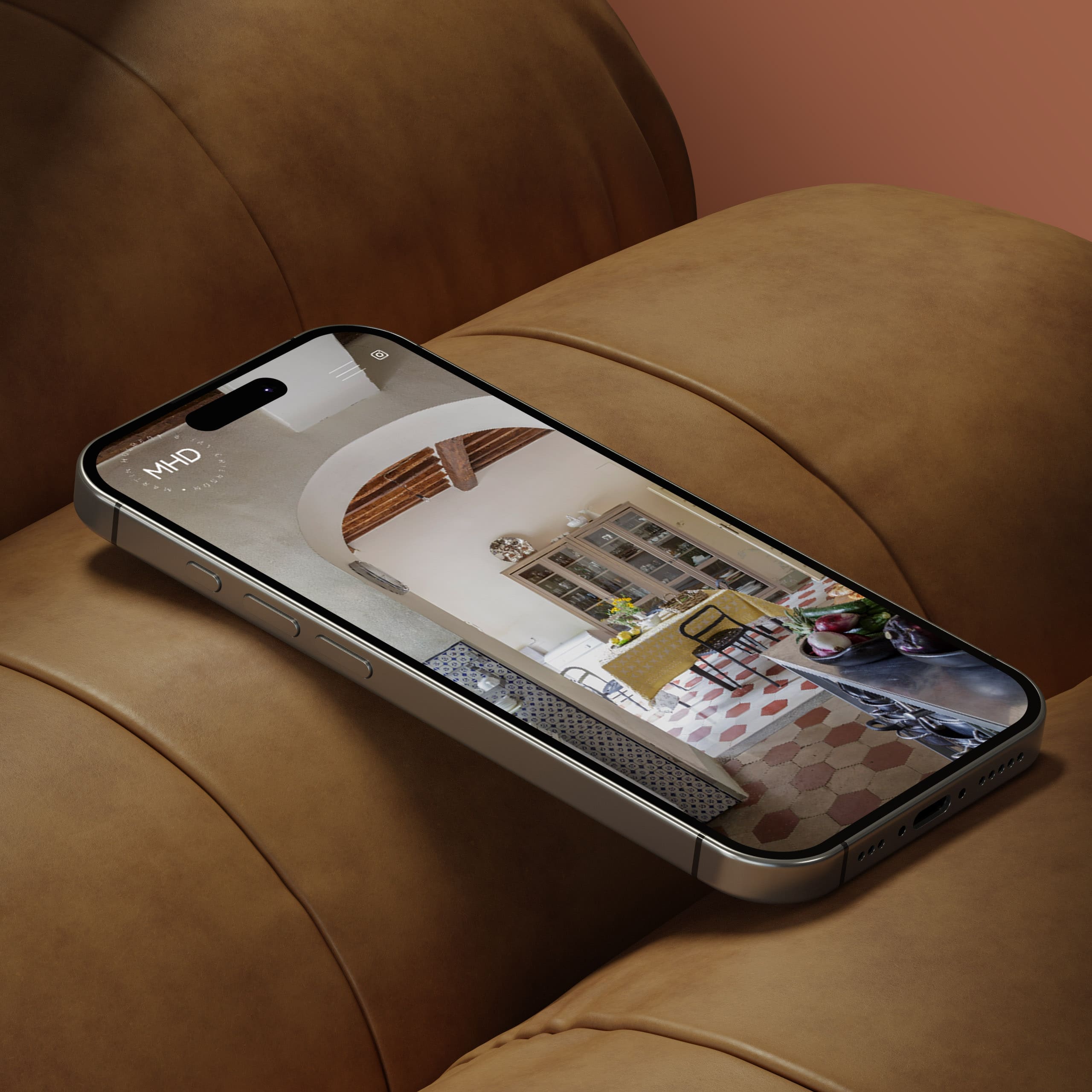A smartphone displaying a kitchen photo on its screen rests on the cushion of a brown leather chair.